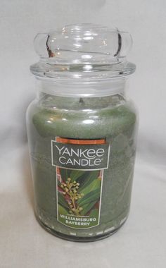 a jar filled with green candles sitting on top of a table