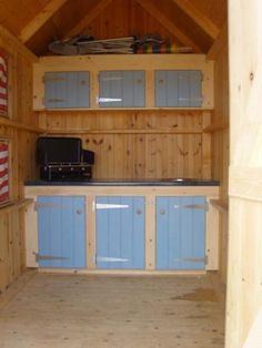 an empty kitchen with blue cabinets and wood flooring on the walls, in a wooden structure