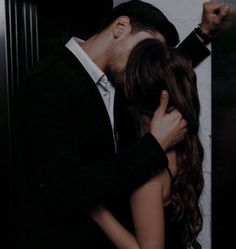 a man and woman kissing in front of an elevator door with their arms around each other