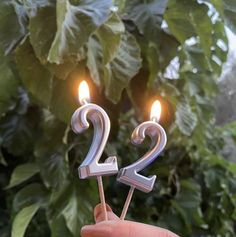 someone is holding two candles in the shape of numbers 2 and 3 on a stick