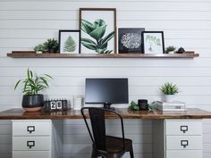 a desk with two computer monitors and some plants on the shelves above it, along with other office supplies