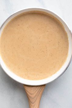 a pan filled with sauce sitting on top of a white counter next to a wooden spoon