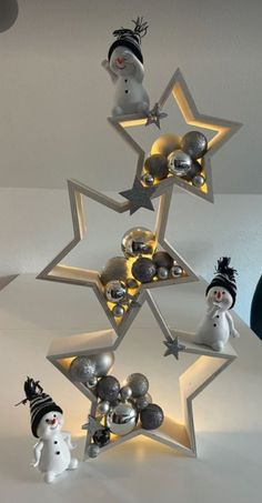 a christmas tree made out of silver balls and snowmen on top of it with lights in the shape of stars