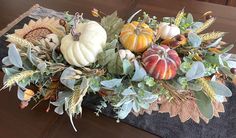 an arrangement of pumpkins, leaves and other autumn decorations on a wooden table top