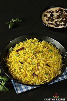 a pan filled with yellow rice next to another pan full of food on top of a table