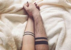 a man and woman holding hands on top of a white bed covered in blankets with their arms wrapped around each other