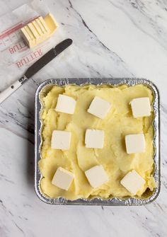 a pan filled with mashed potatoes and butter on top of a marble countertop