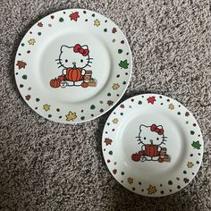 two hello kitty plates sitting on the floor next to each other, one with an orange pumpkin