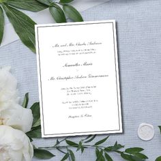 a wedding card with white flowers and greenery on the side, next to a wax seal