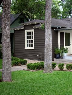 a brown house with white trim and trees