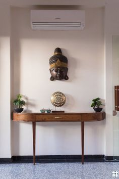 a room with a wooden table and two statues on the wall