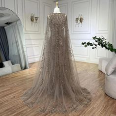 a dress on display in a room with white walls and wooden floors, along with a mirror