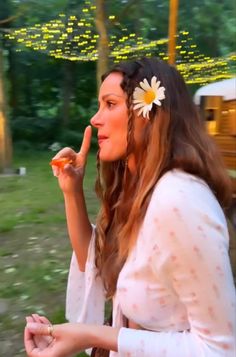 a woman in a white dress is eating pizza and talking on her cell phone outside