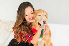 a woman sitting on a couch holding a dog with her tongue out and smiling at the camera