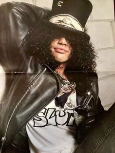 a man with long hair wearing a top hat and leather jacket is posing for the camera