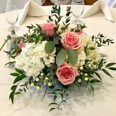 a bouquet of flowers sitting on top of a table next to wine glasses and napkins