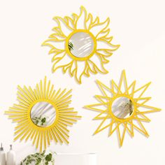 three sun shaped mirrors on the wall above a table and vase with flowers in it