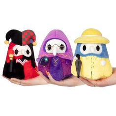 three small stuffed animals sitting in the palm of someone's hand, wearing hats and scarves