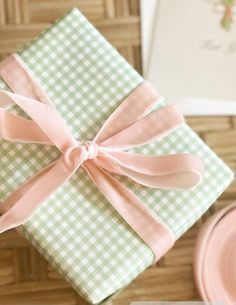 a green and white checkered gift wrapped in pink ribbon with a bow on top