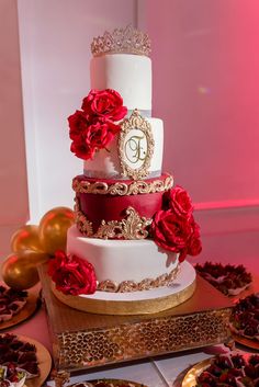 a three tiered wedding cake with red roses on top and gold trimmings