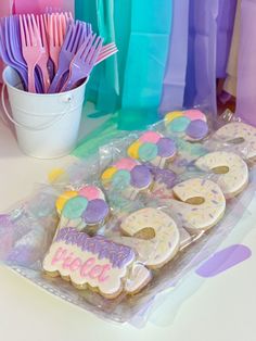 there are some decorated cookies on the table with plastic utensils in front of them