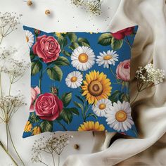 a blue pillow with flowers and leaves on it next to some white flowers in the background