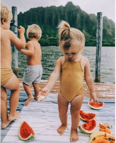 two children in swimsuits playing with watermelon slices