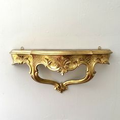 an ornate gold wall shelf against a white wall