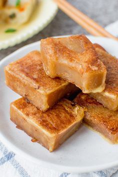 four pieces of toast on a plate with chopsticks next to it and another plate in the background