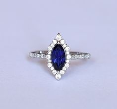 a blue and white diamond ring sitting on top of a table