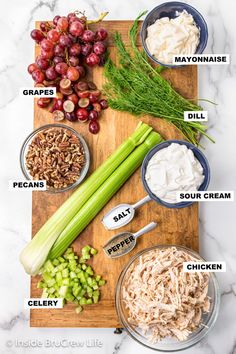 the ingredients to make chicken salad on a cutting board with grapes, celery, dill, sour cream and more