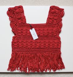 a crocheted red piece of cloth with fringes on it and a price tag