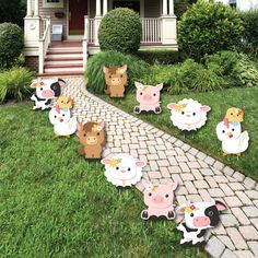 several farm animals are standing in front of a house with lawn decorations on the grass