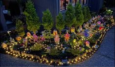 a garden filled with lots of lights next to a building