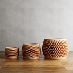 three vases sitting on top of a wooden table next to each other and one is made out of honeycomb