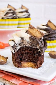 a chocolate cupcake with white frosting and oreo cookies on the top is cut in half