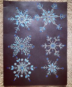 the snowflakes are blue and white on black paper