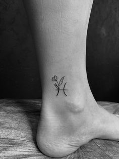 a black and white photo of a person's foot with a small flower on it