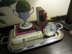 a silver tray with books and a clock on it