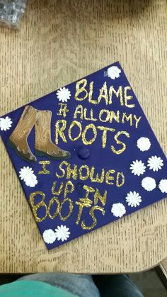 a blue graduation cap with gold writing on it that says, blame i allow my roots i should be born in boots