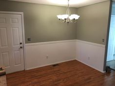 an empty room with hard wood floors and a chandelier