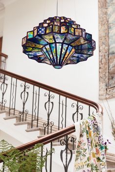 a stained glass chandelier hanging from the ceiling above a stair case in a home