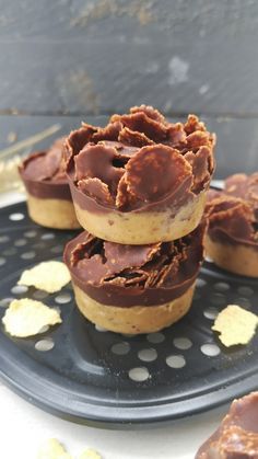 three chocolate covered donuts sitting on top of a black plate with gold flakes