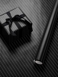 a black and white photo of a present box with a ribbon on it next to a pen