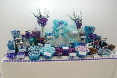 a table topped with lots of blue and purple candies on top of a white table cloth