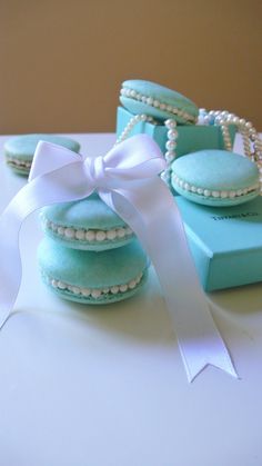 some blue macaroons with pearls and a white ribbon