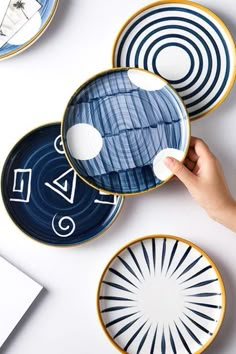 three plates with blue and white designs on them are being held by a person's hand