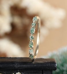 a ring with green and white stones on top of a wooden table in front of a wall