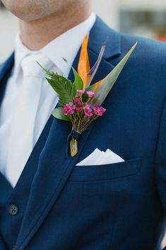 a man wearing a blue suit and flower boutonniere on his lapel