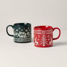 two mugs sitting side by side on top of a white surface with snowflakes